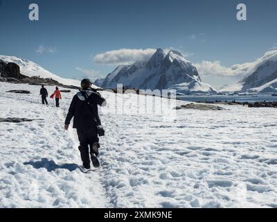 Kreuzfahrttouristen auf Petermann Island mit den Bergen von Graham Land über die Penola Straße im Hintergrund, Wilhelm Archipel, Antarktis Stockfoto