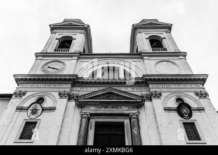 Die krasse Architektur der Kirche Trinita dei Monti hebt sich vom Abendhimmel ab und zeigt die komplizierte Fassade und die zwei Glockentürme dieses berühmten römischen Wahrzeichens. Stockfoto