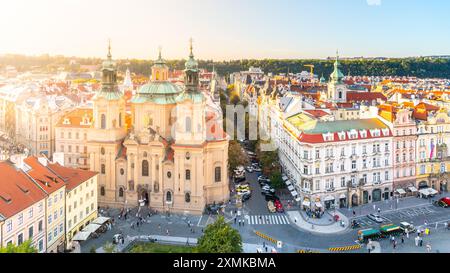 Das goldene Sonnenlicht taucht die Nikolaikirche und umgibt den Altstadtplatz, der die barocke Architektur hervorhebt und warme Töne über dem belebten Stadtplatz ausstrahlt. Prag, Tschechien Stockfoto