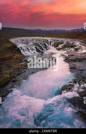 Bruarfoss Wasserfall bei Sonnenuntergang mit schneebedeckten Bergen in Island Stockfoto