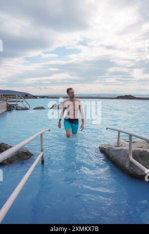 Mann, der durch das milchblaue Wasser des Blue Lagoon Geothermal Spa in Island läuft Stockfoto