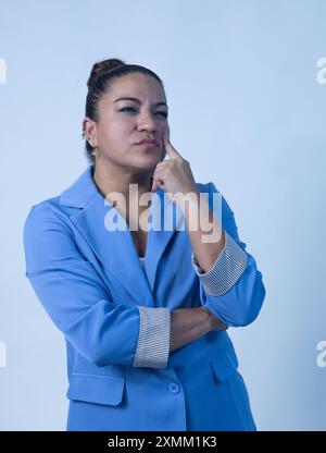 Eine besinnliche Geschäftsfrau posiert in einem stilvollen blauen Anzug und zeigt Selbstvertrauen und Professionalität. Stockfoto