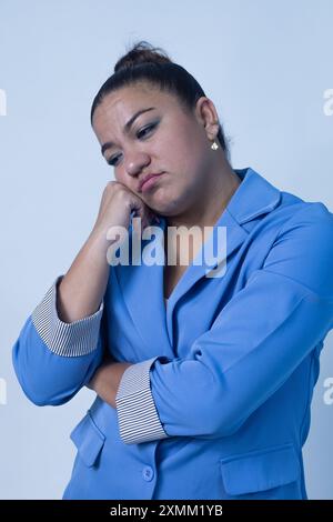 Eine nachdenkliche Frau posiert anmutig in einem stilvollen blauen Anzug, der ihre tiefe Besinnung und Professionalität widerspiegelt Stockfoto