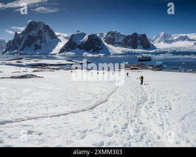 Kreuzfahrttouristen Petermann Island, Wilhelm Archipel, Antarktis mit Mt Scott, Graham Land, im Hintergrund. Stockfoto