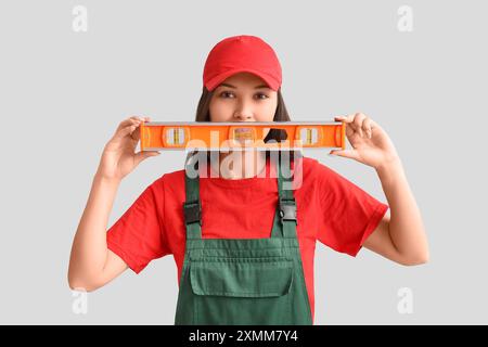 Junge Frau mit Wasserwaage auf grauem Hintergrund Stockfoto