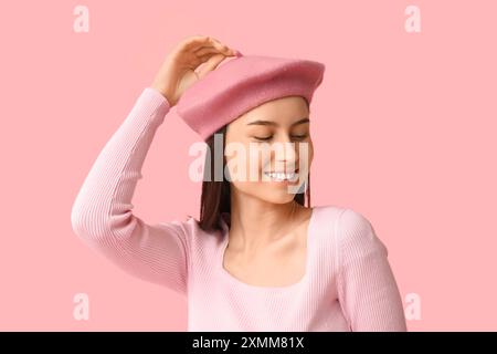 Schöne junge Frau in stilvollem Baskenmütze auf rosa Hintergrund Stockfoto