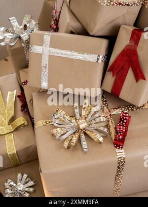 Frohe Weihnachten und frohe Neujahrsgeschichte. Viele Geschenkboxen, umwickelt mit braunem Öko-Craft-Recyclingpapier mit roten, silbernen und goldenen Schleifenbändern Stockfoto