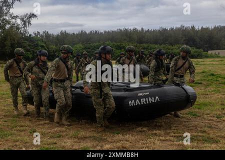 Marineinfanterie-Marines des mexikanischen Marineinfanteriekorps arbeiten zusammen mit malaysischen Soldaten, die dem 8. Bataillon (Fallschirmspringer) zugewiesen sind, zusammen, um Kampfboote für Gummiüberfälle im Marinekorps-Trainingsgebiet Bellows, Waimanalo, Hawaii, während der Übung Rim of the Pacific 2024 am 12. Juli zu tragen. 29 Nationen, 40 Überlandschiffe, drei U-Boote, 14 nationale Landstreitkräfte, mehr als 150 Flugzeuge und 25.000 Mitarbeiter nehmen vom 27. Juni bis 1. August an der RIMPAC Teil. RIMPAC ist die weltweit größte internationale maritime Übung und bietet eine einzigartige Stockfoto