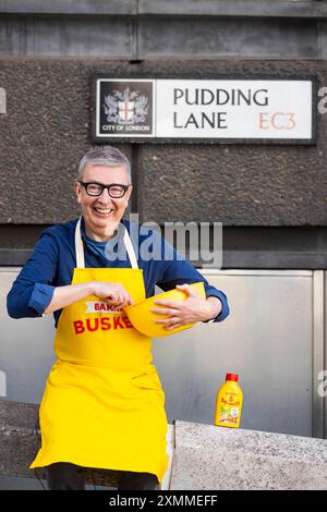 Der ehemalige The Great British Bake Off-Kandidat Howard Middleton erscheint als „Busking Baker“ in der Pudding Lane in London und verteilt Backwaren an Pendler im Rahmen der Veröffentlichung von „Anchor Squeezy“. Ausgabedatum: Montag, 29. Juli 2024. Stockfoto