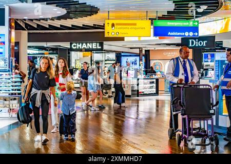 Passagiere, die durch das Duty-Free-Einkaufsviertel in Terminal 3 am Flughafen Heathrow, London, Großbritannien, fahren Stockfoto