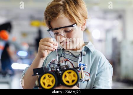 Porträt eines Schülers, der ein Roboterauto im Robotikclub der Schule baut. Kinder, die Robotik in der Grundschule lernen. Wissenschaft für Kinder. Stockfoto