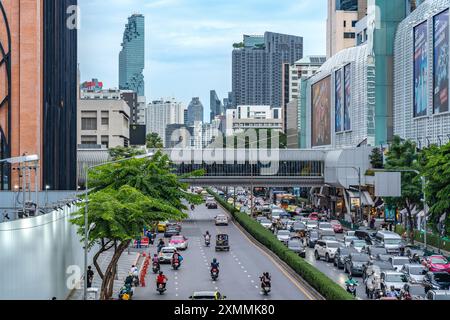 Bangkok, Thailand - 28. Juli 2024 - Blick auf die belebte Straße in der Nähe von Siam Ceter mit dem Hochhaus des Maha Nakorn im Hintergrund Stockfoto