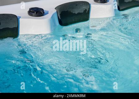 Nahaufnahme mit sprudelndem Wasser im Whirlpool mit Kopfstützen. Blaues Wasser im Whirlpool für entspannende und erfrischende Spa-Erfahrung Stockfoto