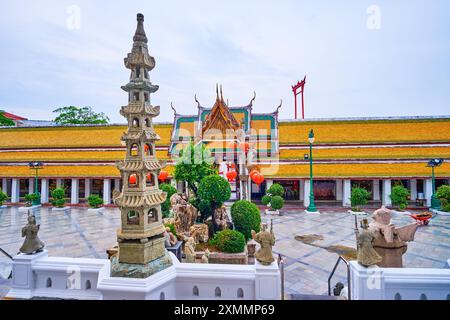 Der Innenhof des Wat Suthat Tempels mit überdachter Galerie, schlanker Säulenlaterne und Riesenflügeln im Hintergrund, Bangkok, Thailand Stockfoto