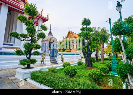 Die farbenfrohe Seitentür zu Ubosot von Wat Suthat mit zwei Wächtern, Bangkok, Thailand Stockfoto