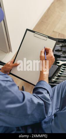 Rückansicht eines professionellen Handwerkers mit offener Werkzeugtasche auf dem Boden der Küche Stockfoto