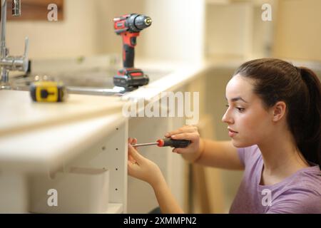 Frau, die Möbel selbst in der Küche installiert, das Haus restauriert Stockfoto