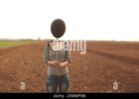 Der Kopf der Frau wird durch einen schwarzen Ballon ersetzt Stockfoto