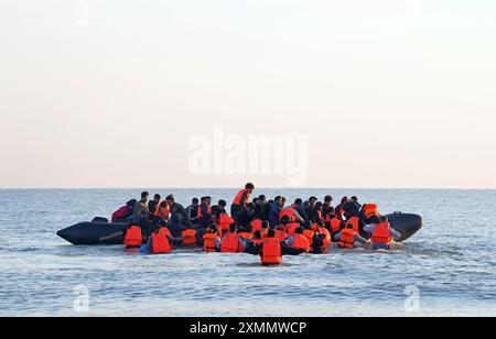 Eine Gruppe von Menschen, die als Migranten gelten, waten durch das Meer, um sich an Bord eines kleinen Bootes vor dem Strand in Gravelines, Frankreich, zu stürzen. Bilddatum: Montag, 29. Juli 2024. Stockfoto