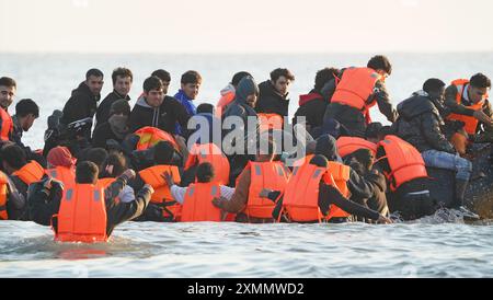 Eine Gruppe von Menschen, die als Migranten gelten, waten durch das Meer, um sich an Bord eines kleinen Bootes vor dem Strand in Gravelines, Frankreich, zu stürzen. Bilddatum: Montag, 29. Juli 2024. Stockfoto