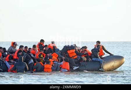 Eine Gruppe von Menschen, die als Migranten gelten, waten durch das Meer, um sich an Bord eines kleinen Bootes vor dem Strand in Gravelines, Frankreich, zu stürzen. Bilddatum: Montag, 29. Juli 2024. Stockfoto