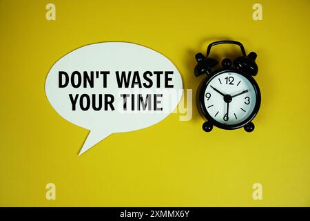 Verschwenden Sie Ihre Zeit nicht mit Text für Sprachgeblätter mit Wecker Draufsicht auf gelbem Hintergrund Stockfoto