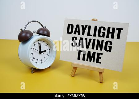 Text zur Sommerzeit auf Papierkarte mit Wecker auf gelbem Hintergrund Stockfoto