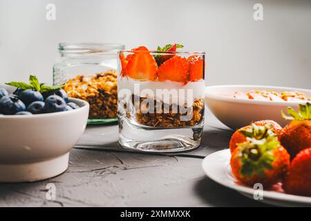 Dessert aus Erdbeeren und Heidelbeeren, Müsli und Joghurt, Hüttenkäse und Sahne. Ein zartes Parfait für ein gesundes Frühstück in einer weißen Schüssel und Stockfoto