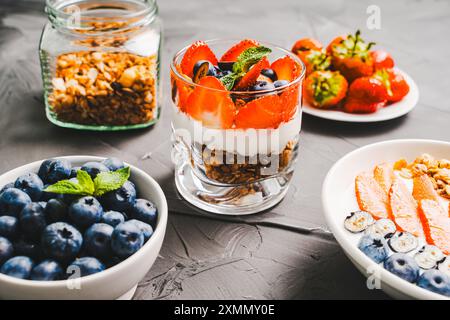 Dessert aus Erdbeeren und Heidelbeeren, Müsli und Joghurt, Hüttenkäse und Sahne. Ein zartes Parfait für ein gesundes Frühstück in einer weißen Schüssel und Stockfoto