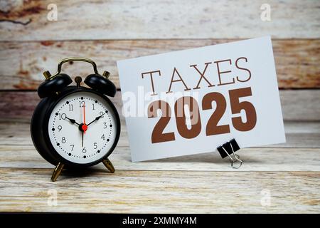 Steuern 2025 Text mit Wecker auf hölzernem Hintergrund Stockfoto