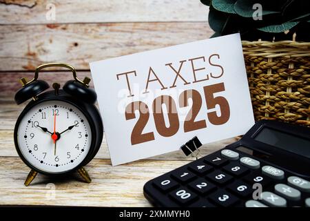 Steuern 2025 Text mit Wecker und Taschenrechner auf hölzernem Hintergrund Stockfoto