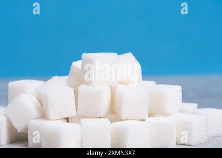 Zuckerwürfel auf blauem Hintergrund. Ernährung und gesundes Ernährungskonzept Stockfoto