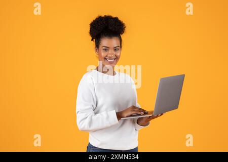 Lächelnde Frau Mit Laptop Vor Gelbem Hintergrund Stockfoto