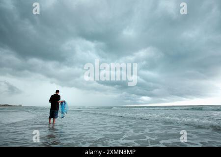 Ein Mann fischt mit einem Netz unter stürmischem, bewölktem Himmel in den Gewässern von Wrightsville Beach. Stockfoto