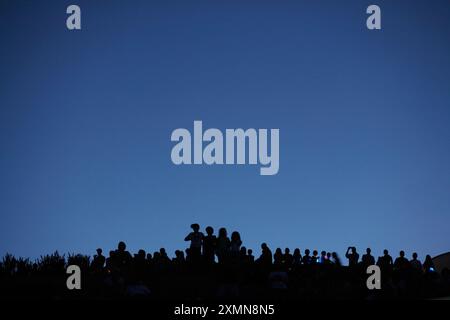 Eine Menschenmenge ist vor einem blauen Abendhimmel zu sehen, während sie am 4. Juli ein Feuerwerk sehen Stockfoto