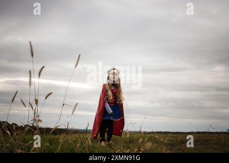 Glückliches kleines Mädchen mit rotem cape-Superhelden Stockfoto