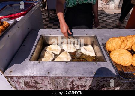 Eine Frau brät Donuts in einer Pfanne Stockfoto