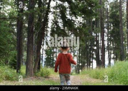 Das kleine Mädchen sammelt Käfer, während es durch den Wald geht. Stockfoto