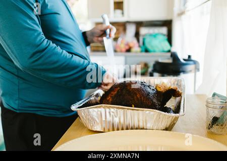 Mann schnitzt truthahn an Thanksgiving zu Hause zum Abendessen in der Küche Stockfoto