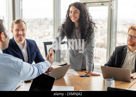 Geschäftsfrau schüttelt bei einem modernen Bürotreffen die Hand mit Kollegen Stockfoto