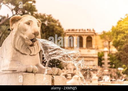 Das warme Leuchten des Sonnenuntergangs beleuchtet den Löwenbrunnen am Popolo Square, mit Wasser, das anmutig aus der Löwenmündung strömt. Rom, Italien Stockfoto