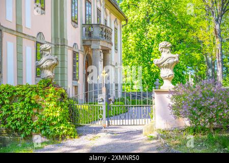 Blick auf das Eingangstor zum kleinen Barockschloss Potstejn in der Tschechischen Republik. Das Tor besteht aus Schmiedeeisen und wird von zwei Steinstatuen flankiert. Das Schloss ist im Hintergrund sichtbar. Stockfoto