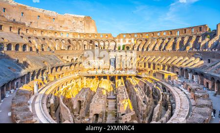 Ein Blick auf das Kolosseum in Rom bei Sonnenuntergang und Blick hinunter in die Arena. Das antike Amphitheater ist in warmes Licht getaucht und bietet Besuchern die Möglichkeit, die historische Stätte zu erkunden. Stockfoto