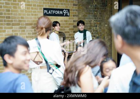 London, UK, 20. juli 2024. Japaner geben vor, einen Zauberstab in Bahnsteig 9 3-4 am Bahnhof King's Cross zu halten Stockfoto