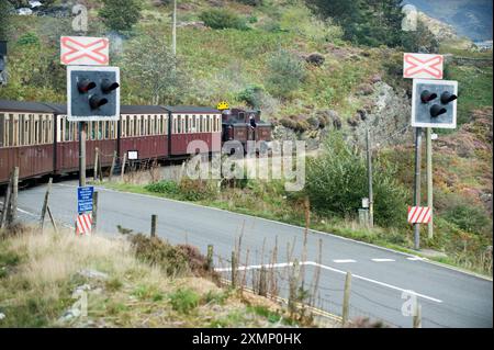 Bild von Roger Bamber : 23 September 2011 : 2ft. Die Schmalspurdampflokomotive Fairlie „Merddin Emrys“ fährt ihren Zug über einen Bahnübergang über eine Straße nach Porthmadog auf der Ffestiniog Railway, die zwischen Porthmadog und Blaenau Ffestiniog in Snowdonia, Nordwales, Großbritannien verkehrt. Stockfoto