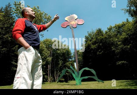 Foto von Roger Bamber: 29 Mai 2003: Flower Power... Der Bildhauer Marc Quinn mit seiner riesigen 12 Meter hohen, 2,2 Tonnen schweren Orchidee aus Stahl mit dem Titel „The Surüberwälming World of Desire (Paphiopedilum Winston Churchill Hybrid“ in der Sculpture at Goodwood, nahe Chichester, West Sussex. Das Stück entstand aus den eigenen Frozen Flower Skulpturen der Künstler. Er ist auch bekannt für seine Experimente mit verschiedenen Materialien wie Blut, Blei und Eis. Stockfoto