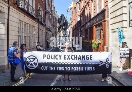 London, Großbritannien. Juli 2024. Ein Demonstrant, der ein Sensenmann Kostüm trägt, sitzt auf einer Struktur, die von Aktivisten der Extinction Rebellion errichtet wurde, während sie vor Policy Exchange, einem einflussreichen rechten Think Tank, protestieren und fordern, dass sie Verbindungen zu fossilen Brennstoffen abbauen. Quelle: Vuk Valcic/Alamy Live News Stockfoto