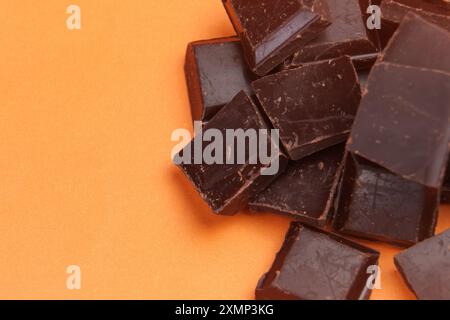 Reine, dunkle Bitterschokoladenstücke aus biologischem Anbau auf einem kreativen orangen Hintergrund. Makroaufnahme Stockfoto