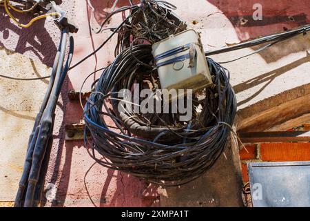 Komplizierte, verworrene Drähte umgeben einen Schaltkasten an einer lebendigen Wand in Tarragona. Stockfoto