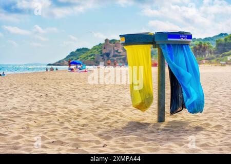 Dreifache Müllbeutelhalter mit bunten Taschen an einem ruhigen Strand von Tarragona. Stockfoto